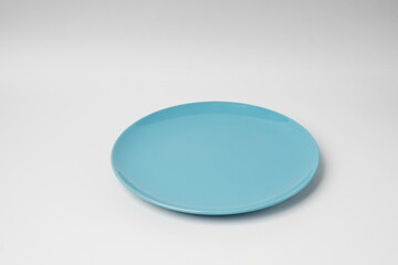 Blue plate, light blue ceramic plate isolated on a white background, shot in a studio with soft lighting