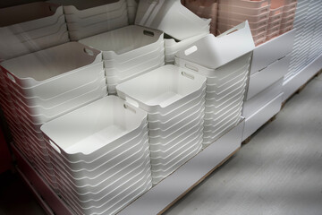 Stacked white plastic storage bins in a retail environment showcasing organization and minimalistic design with copy space