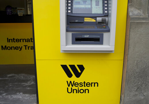Rome, Italy - May 14, 2025: Western Union ATM machine in bright yellow exterior for international money transfer services with clear branding