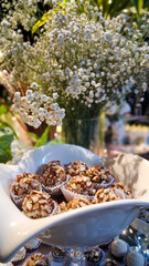 Delicious wedding desserts with flowers behind.
