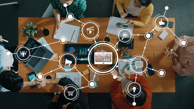 Aerial view of a diverse team engaged in a collaborative workspace, utilizing digital tools and graphics to devise effective advertising and social media strategies. Amity - Powered by Adobe