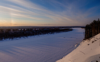 Top view of a winter landscape - frozen river and snowy forest