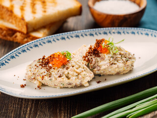 Fish appetizer forshmak - minced meat from herring fish, decorated caviar on plate. Traditional Jewish cuisine dish vorschmack forshmak made of herring fillet as independent dish on wooden background