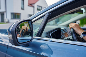 Female hands on steering wheel reflecting in mirror. Woman driving car