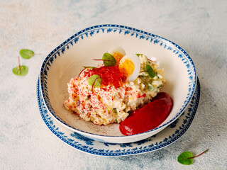 Mayonnaise salad with crab meat, decorated with beetroot mousse in restaurant-style plating. Imitation crab salad with crab sticks or crab meat and eggs in bowl on white marble background
