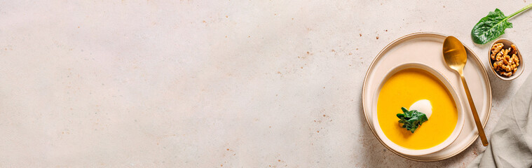 Pumpkin cream-soup served spinach, nuts, sour cream. Banner. Tasty Homemade Pumpkin, Sweet Potato or Carrot Soup in Bowl on Neutral Pastel Background. Cozy autumn comfort food. Copy space. Top view