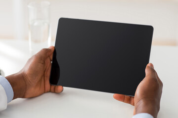 Technology for treat. Unrecognizable african american doctor using digital tablet with blank screen, empty space, mockup for ad. Man therapist sitting at workplace in office, closeup, crop