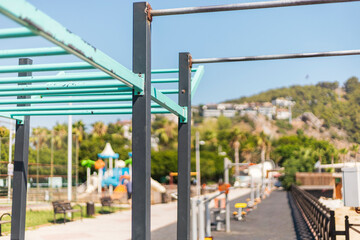 A vibrant outdoor fitness area features various exercise equipment alongside a colorful playground. Sunlight illuminates the scene, enhancing the lively atmosphere of this public space
