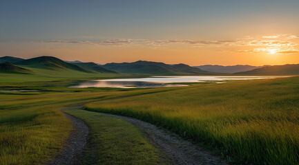 Fototapeta premium A beautiful sunset over the grassy hills of Mongolian Flamingo Lake, with an old dirt road leading to it