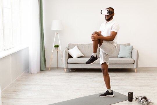 Black Guy Training Wearing Virtual Reality Headset Doing Legs Exercise Standing Having Workout At Home. Sport With Augmented Reality App, Future Of Fitness Gym, Technology Concept - Powered by Adobe