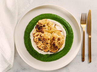 Cauliflower steak with green and white puree. Grilled cauliflower as vegan and vegetarian food concept. Healthy food ideas and menu.