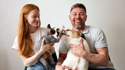 Happy couple with their dog and cat enjoying playful moments together