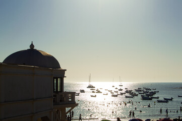 Historic La Palma spa pavilion and moored boats at sunset on La Caleta beach in Cadiz Spain © Sara