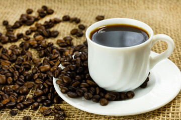 A white cup filled with black coffee sits on a saucer. 