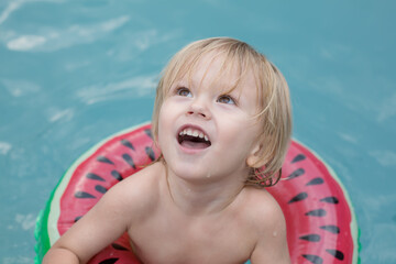 Happy child in watermelon float in the pool