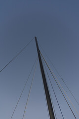 A vertical low-angle shot captures the mast of a sailboat and its rigging lines reaching into a clear, twilight sky, emphasizing height and simplicity.