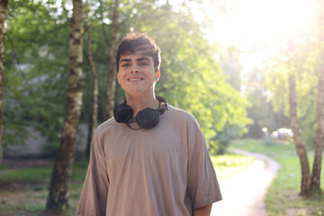 Portrait of a cheerful teenage boy around 16 years old. Confident Teenage Boy with Headphones in...