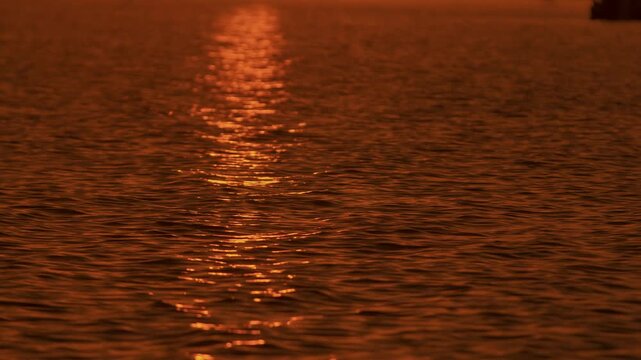 Stunning view of golden path of setting sun on surface of water with gentle waves. Concept of silence and pacification