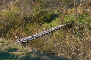 Small decrepit pedestrian bridge across narrow riverbed, Skhidnytsia, Western Ukraine.