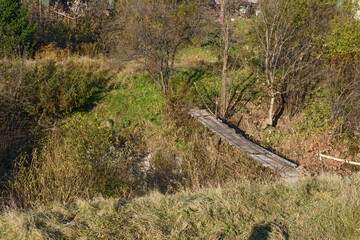 Small decrepit pedestrian bridge across narrow riverbed, Skhidnytsia, Western Ukraine.