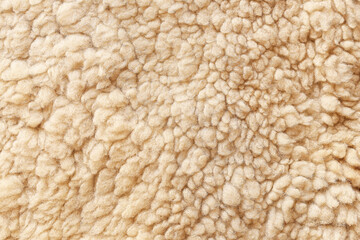 Soft beige wool texture background. Closeup of fluffy warm fleece surface. Natural sheep wool fabric. Cozy textile pattern. Comfortable insulating material for clothing, blankets and crafts.