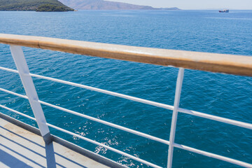 peaceful, wide-angle shot from a boat's deck, showing the vast expanse of the deep blue sea, a distant mountainous coastline