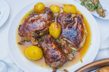 Delicious roasted lamb and golden potatoes in gravy served on a white plate, showcasing traditional Mediterranean cuisine and comfort food.