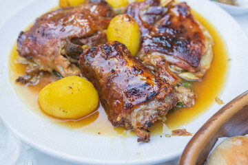 Delicious roasted lamb and golden potatoes in gravy served on a white plate, showcasing traditional Mediterranean cuisine and comfort food.