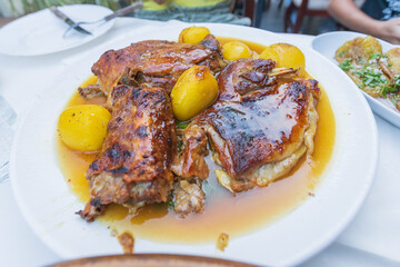 Delicious roasted lamb and golden potatoes in gravy served on a white plate, showcasing traditional Mediterranean cuisine and comfort food.