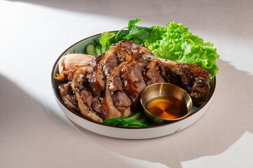 Traditional Korean dish with sliced roasted pork leg, fresh lettuce, kimchi, sesame seeds, and soy sauce. Tasty Asian cuisine captured in natural daylight.