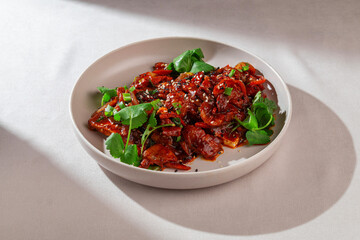 Stir-fried shrimp in Korean spicy gochujang sauce with sesame seeds, onion and fresh greens served on a ceramic plate under natural light