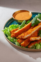 Breaded chicken katsu slices served with steamed rice topped with sesame seeds, spicy dipping sauce and fresh cilantro on a blue ceramic plate