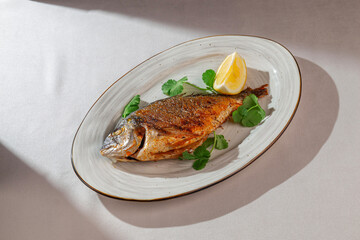 Whole grilled dorado fish served on a rustic ceramic plate with fresh cilantro and lemon wedge, beautifully lit in natural hard light