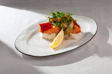 An exquisite grilled salmon fillet served on a bed of fluffy white rice, garnished with fresh cucumber ribbons, vibrant pea shoots, and a lemon wedge