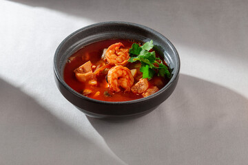 A vibrant and flavorful bowl of spicy Thai Tom Yum soup, generously filled with succulent shrimps and fresh green cilantro, perfect for a warming meal