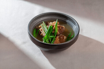 A rich and comforting bowl of clear oxtail beef broth soup, generously garnished with fresh green onions and tender meat, perfect for a warming meal