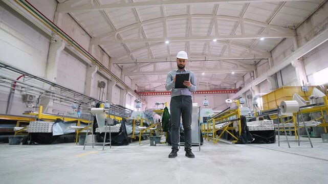 Industrial engineer taking notes on tablet in window factory