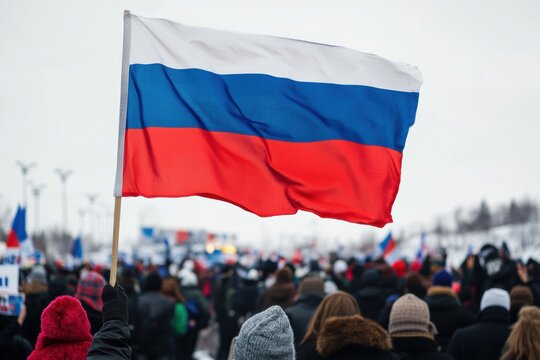 Patriotic rally with Russian flag prominently displayed among gathered supporters in winter