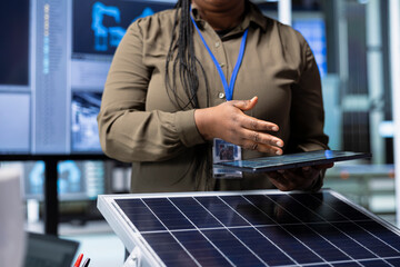 Industrial plant research and development worker analyzes PV materials using tablet to study how to harness sun power. Factory expert evaluates solar cells designs using device to improve efficiency
