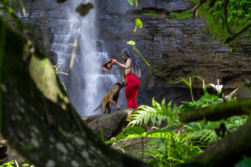 Beautiful woman with her pet Belgian Malinois at a waterfall
