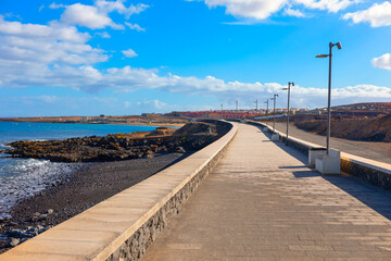 Coastal walkway stretches along the Atlantic shore in Fuerteventura.  Paved promenade winds along...