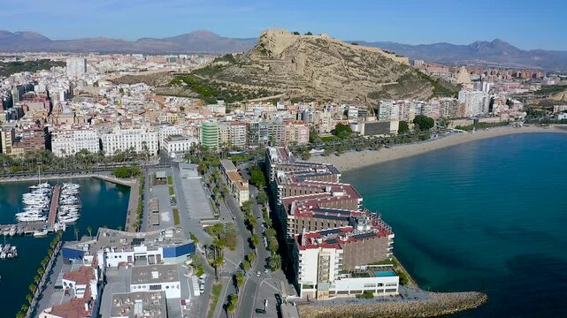 Aerial view of Postiguet Beach and the first line of buildings next to Santa Barbara Fortress in the Mediterranean city of Alicante, Spain. 