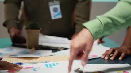 Business colleagues attending in a late night briefing session for teamwork, exchanging documents and reviewing finance updates. Aligning objectives through problem solving. Camera B.