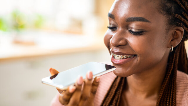 Smiling Young Black Female Using Virtual Voice Assistant Option On Smartphone, Positive African American Lady With Dental Braces Recording Audio Message With Mobile Phone, Closeup With Free Space