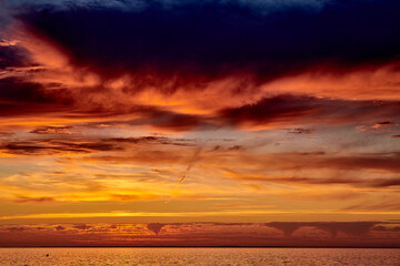 sunrise at sea behind clouds on a summer morning