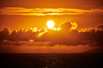 sunrise at sea behind clouds on a summer morning