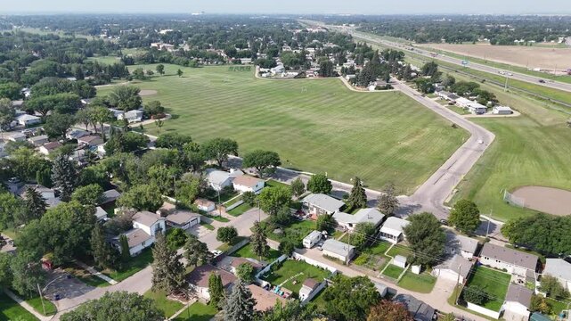 Large field with a few houses in the background. The houses are all different sizes and are located at various distances from the field