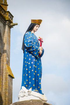Sculpture of the crowned Virgin Mary on pillar outside the Basilica of Pontmain in France, vertical