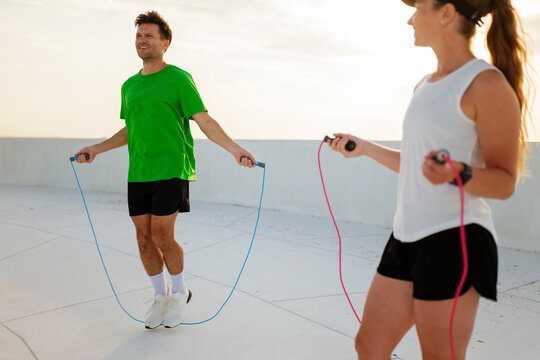 Exercising with jump ropes on a rooftop during a vibrant sunset, promoting fitness and health in a lively urban atmosphere