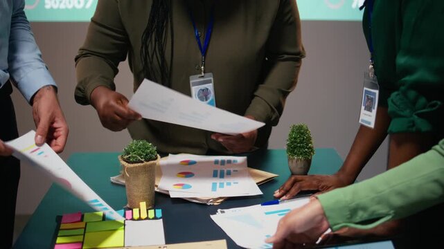 Diverse team members meeting after hours to share data reports, discuss business intel and prepare forecasts for upcoming presentations to enterprise shareholders after hours. Camera A. - Powered by Adobe